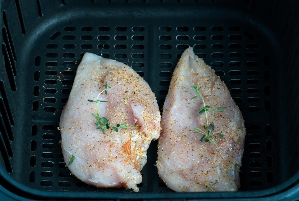 Air fryer chicken breast cooking inside basket at 375°F