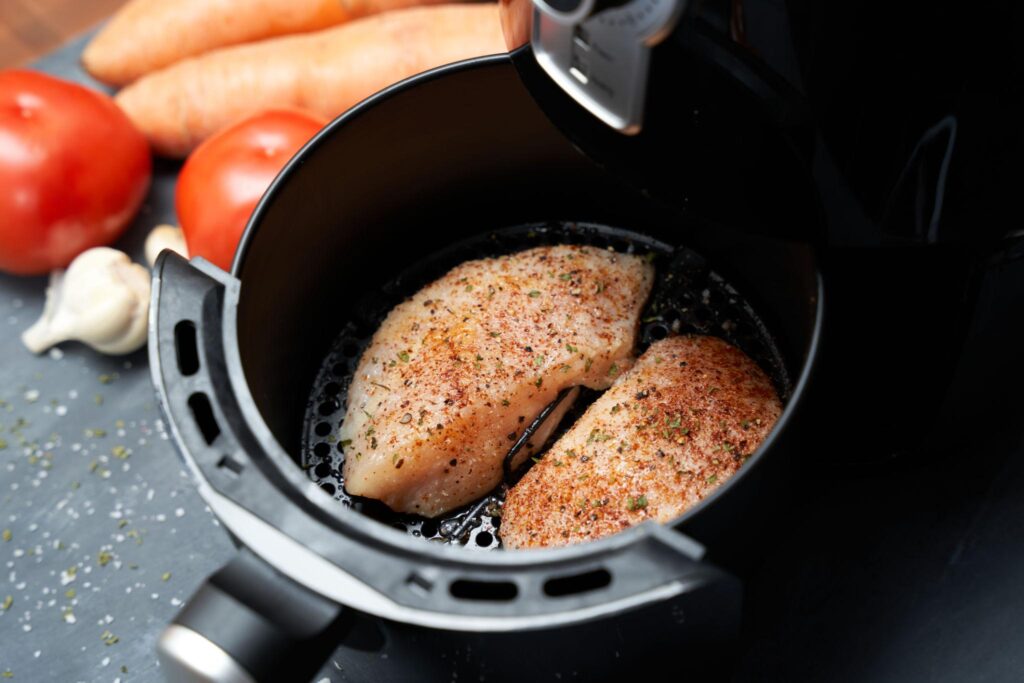 Air fryer chicken breast cooking inside basket at 375°F